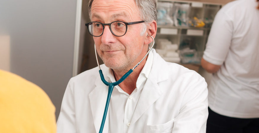 Dr. Hans Haltmayer mit Stethoskop untersucht Patient*in