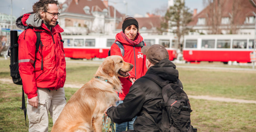 sam 2er-Team im Gespräch mit einem Herrn mit Hund im öffentlichen Raum in Wien