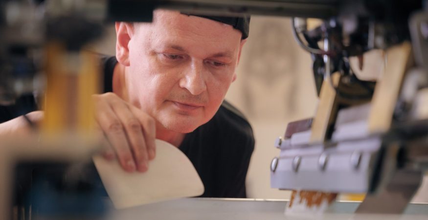 Nahaufnahme: Konzentration im Gesicht des Mitarbeiters, der eine Textildruckmaschine bedient