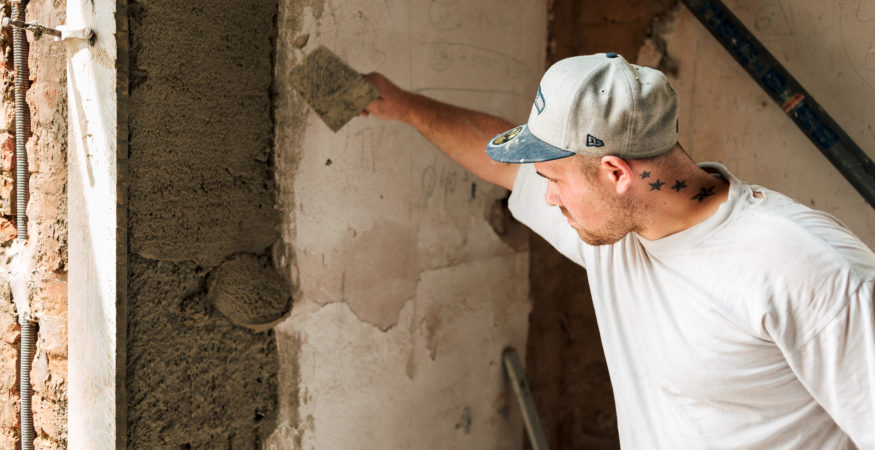 Bauarbeiter arbeitet mit der Maurerkelle am Verputzen einer Wand