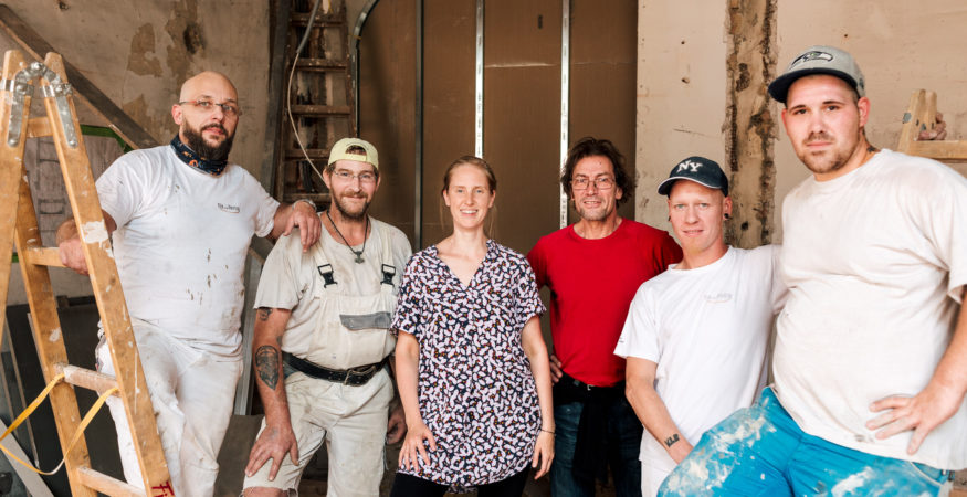 Gruppenbild auf der Baustelle: 4 Bauarbeiter, Bereichsleiter Walter Wojcik und die Bauherrin