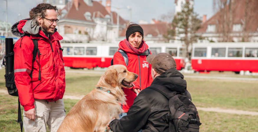 sam 2er-Team im Gespräch mit einem Herrn mit Hund im öffentlichen Raum in Wien