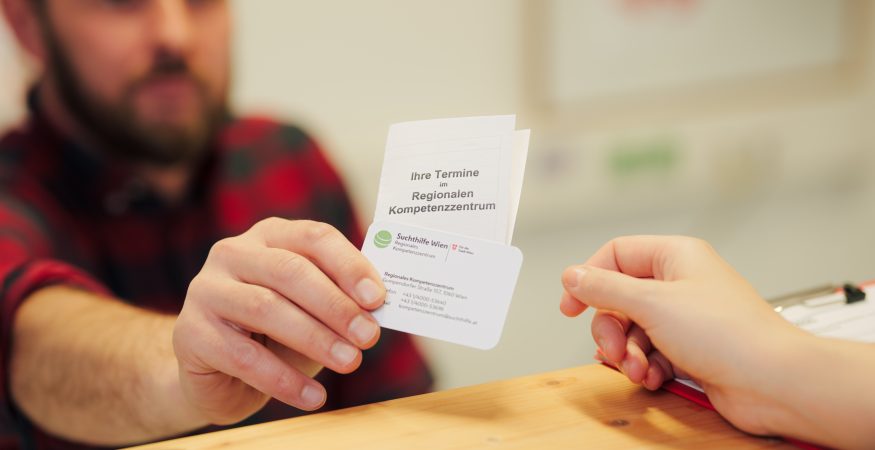 Nahaufnahme: ein Mitarbeiter übergibt seine Visitenkarte und eine Terminkarte an eine Klientin